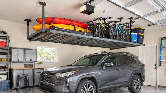 Kayaks and bikes stored overhead on a motorized garage ceiling lift above a parked car.