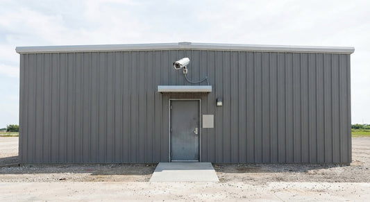 Grey corrugated metal building with security camera above doorway.