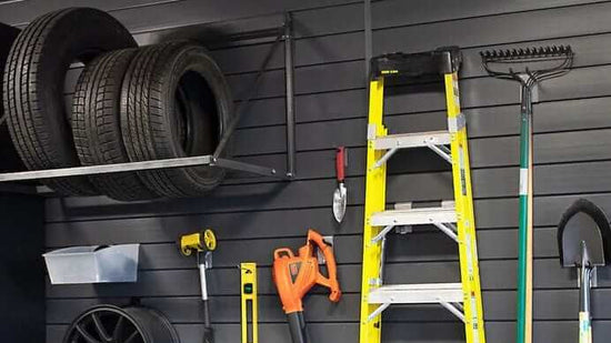 Garage organized from floor to ceiling with an overhead storage rack above a slatwall of tools, ladder and yard equipment